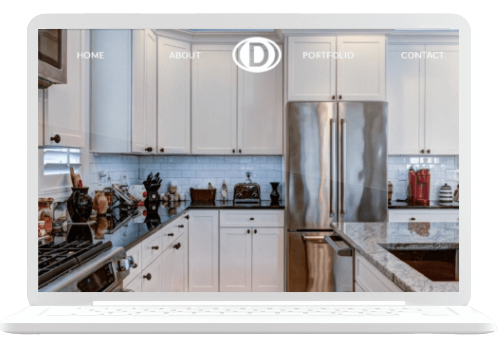 A laptop screen displays a website featuring a modern kitchen. The kitchen has white cabinetry, stainless steel appliances, and a granite countertop. The website menu items shown are "Home," "About," "Portfolio," and "Contact.